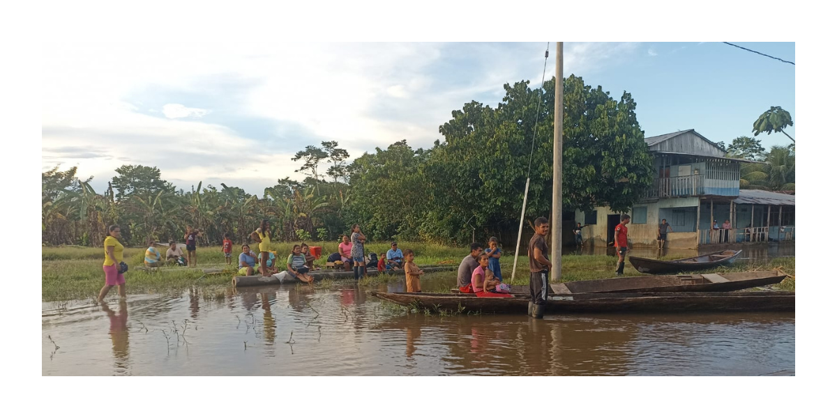 families stand in flooded field next to homes