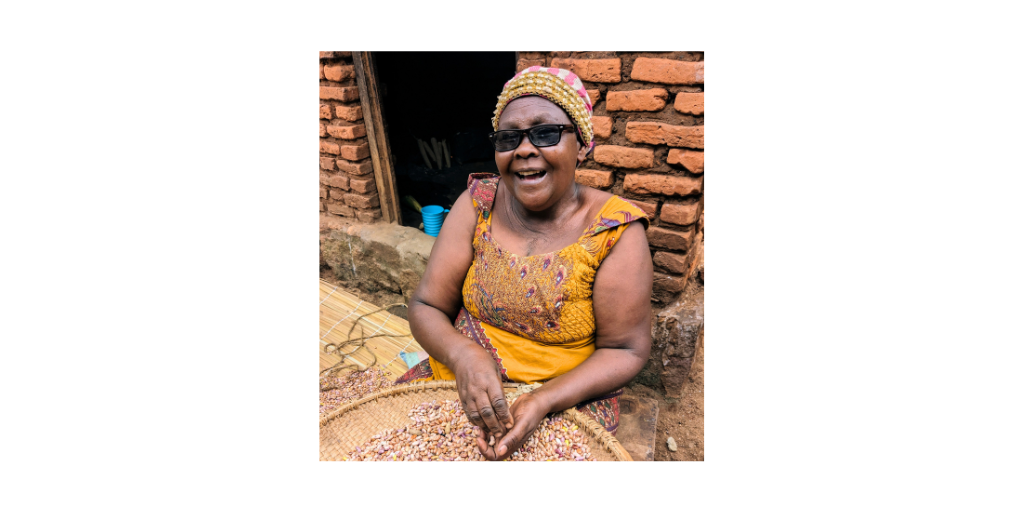 Fabiola, a single mom, is pictured smiling in front of a brick wall. She is sorting beans in a basket.