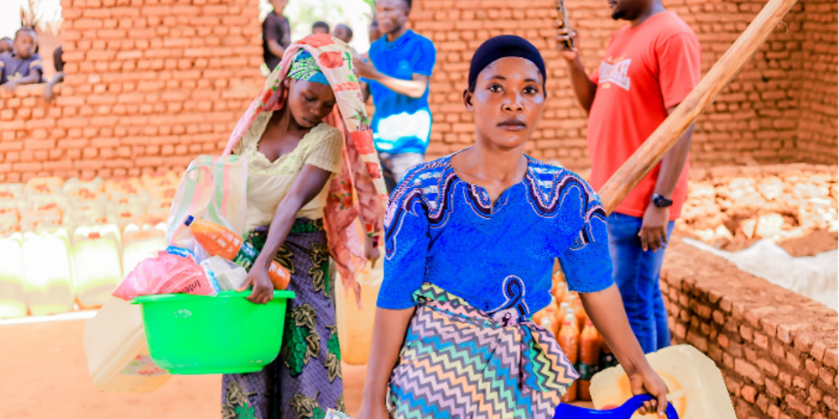 Two women carrying food packs and other supplies