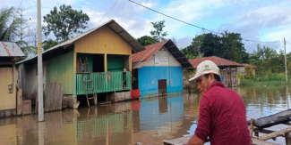 A man surveys flooded houses from a boat
